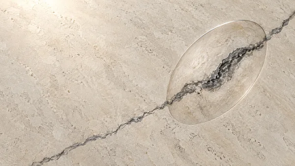 A warm beige limestone-like mineral texture fills a landscape frame, with a dark diagonal seam that widens and curves through a large translucent tilted…