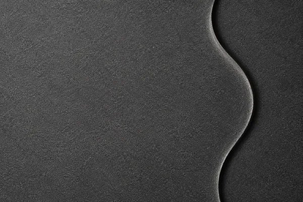 A charcoal-gray textured surface fills the frame, with a broad dark S-shaped recessed channel and a thin silver-gray highlight curving vertically near the…