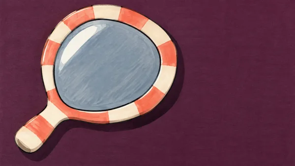 An oversized hand mirror lies diagonally on a deep-plum surface, with a rounded slate-blue face, a coral-and-cream striped frame, and a short handle pointing…